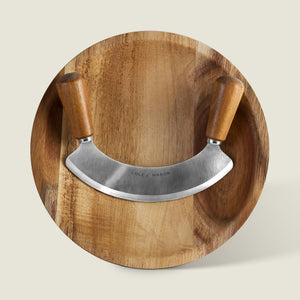 The Cole & Mason Ashden Mezzaluna and Board includes a wooden chopping board with a curved stainless steel mezzaluna, featuring wooden handles—ideal for efficient food preparation.