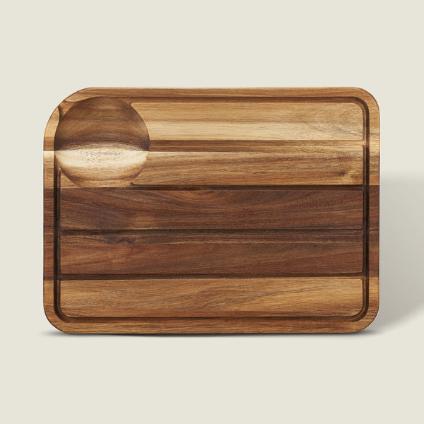The Cole & Mason Berden Acacia Carving Board features a rectangular design with rounded corners, a recessed juice groove, and a circular indentation. Its striped acacia wood pattern adds style to your kitchen.