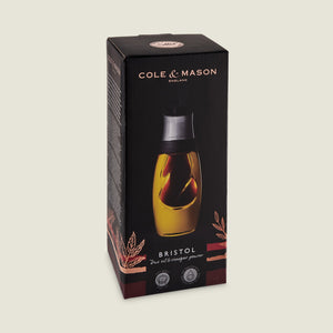 The Cole & Mason Bristol Duo Oil & Vinegar Pourer features a dual-chamber glass design for mess-free dispensing and comes in black and gold packaging with decorative leaf graphics.
