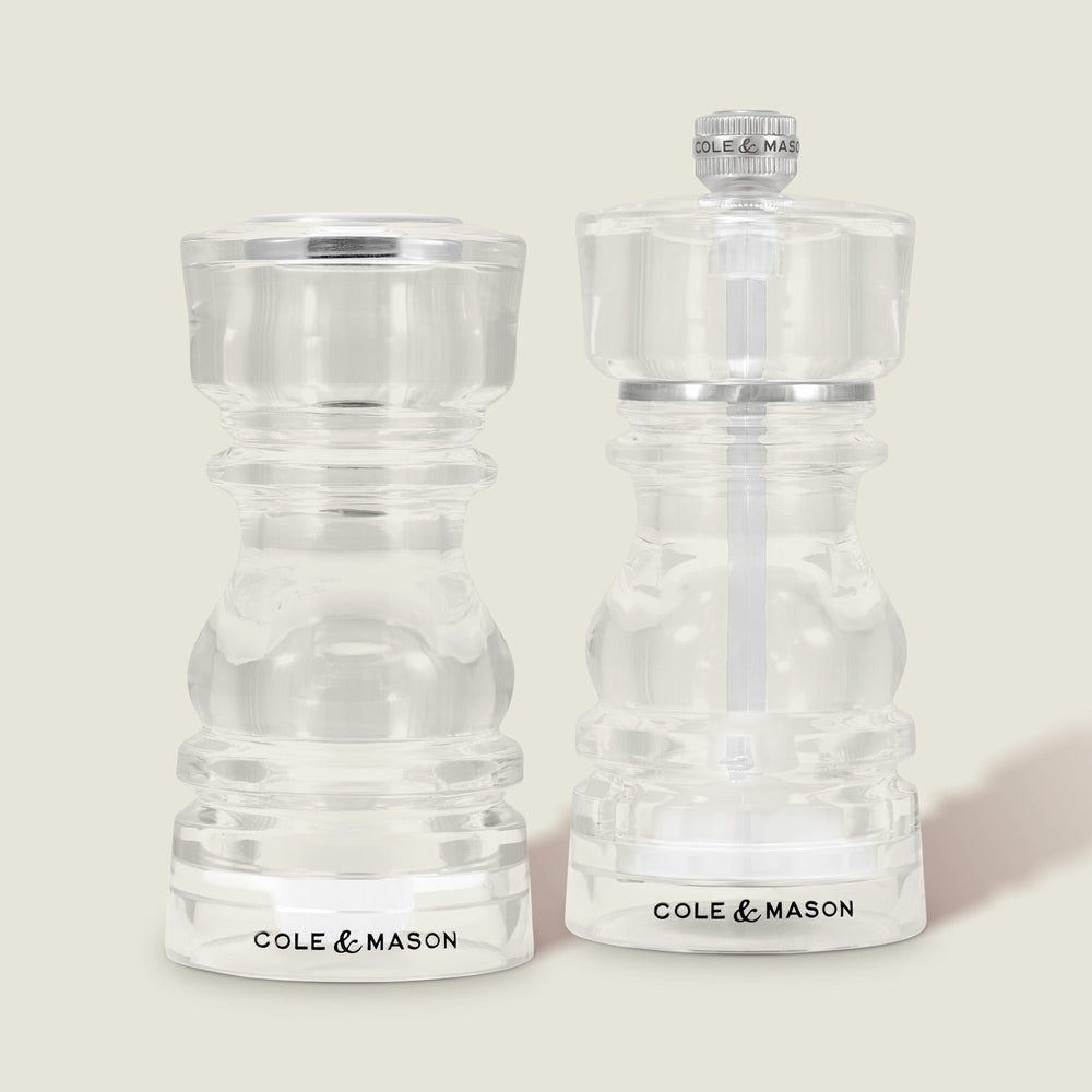 The Cole & Mason London Acrylic Salt Shaker & Pepper Mill Set features two clear grinders with contemporary design details, displayed side by side—ideal for stylish seasoning on any modern table.