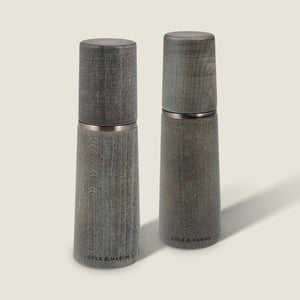 Two Marlow Grey Beech Salt & Pepper Mills by Cole & Mason UK, featuring a smooth tapered shape and wood grain, stand upright on a light background with an adjustable grinding mechanism for custom seasoning.