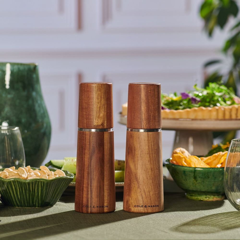 The Cole & Mason UK Marlow Natural Acacia Salt & Pepper Mills feature a smooth, polished finish, silver accents, minimalist design, and an adjustable grinding mechanism for precise seasoning.
